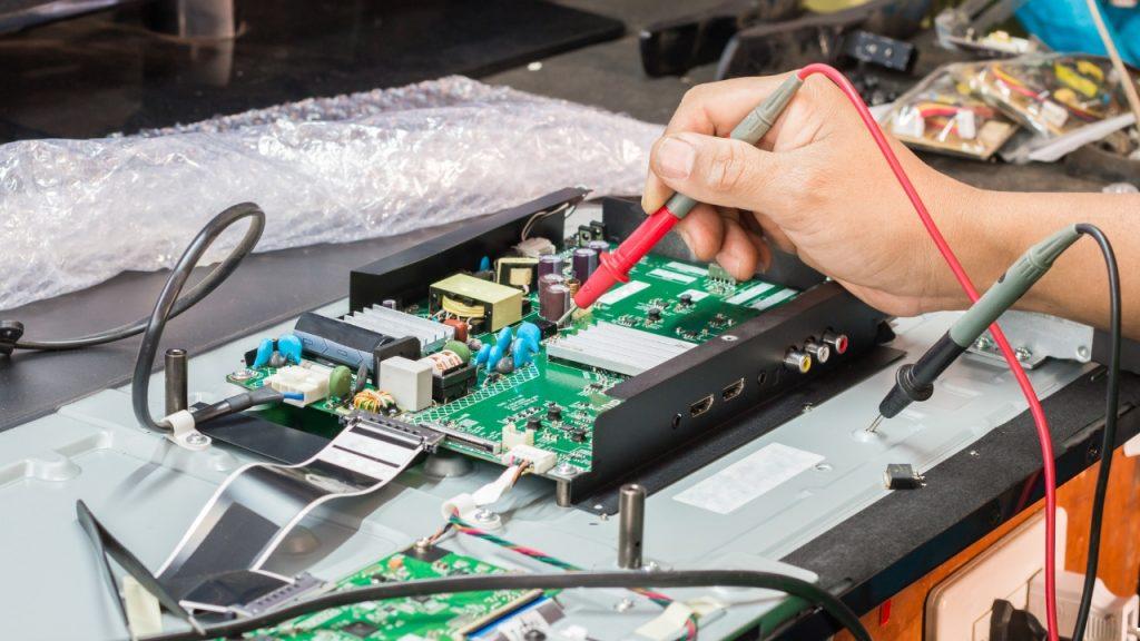 Technician using digital multimeter for advanced diagnostics on TV power supply and circuit board